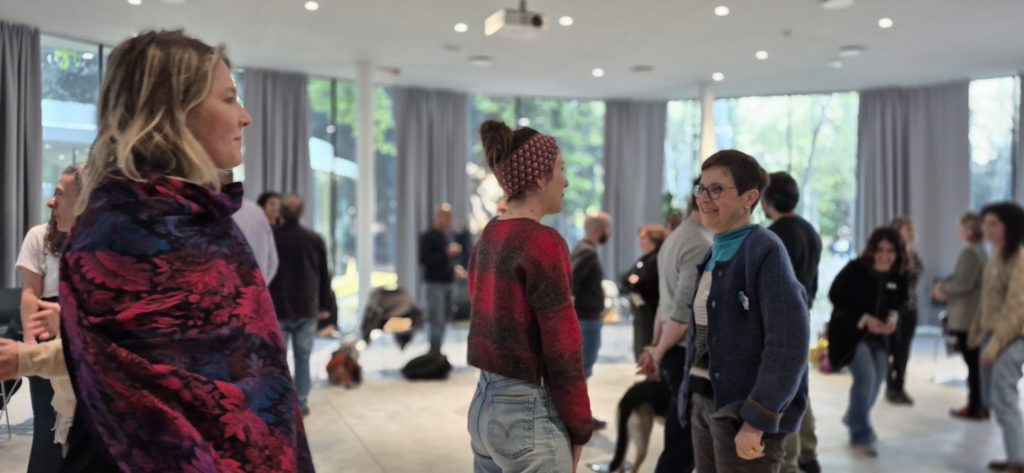 Alcuni partecipanti inquadrati in piedi, mentre parlano tra loro durante un incontro