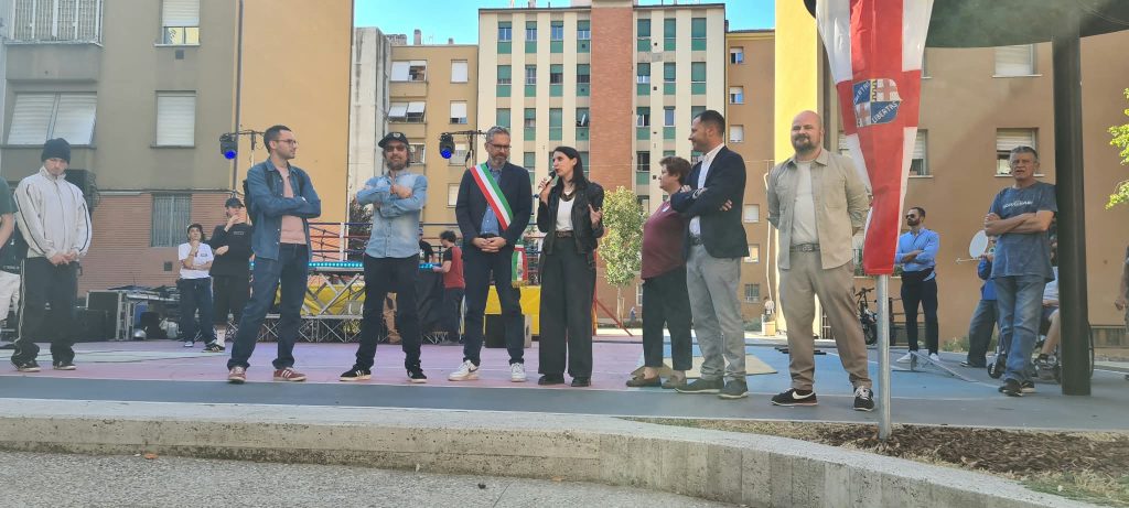 Il sindaco, la vicesindaca, il fratello di Joe Cassano, il presidente di ACER, il Presidente del Quartiere in attesa di svelare la targa di intitolazione del giardino, sullo sfondo i palazzi delle Popolarissime