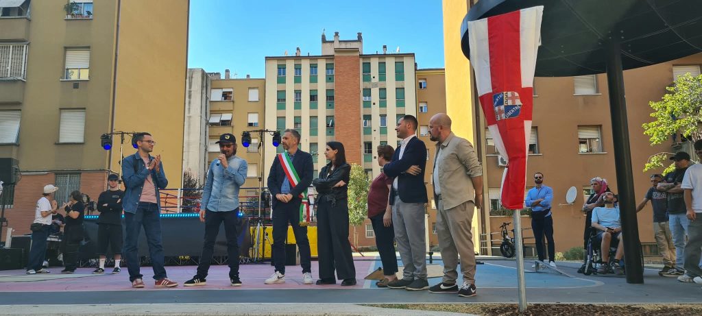 Il sindaco, la vicesindaca, il fratello di Joe Cassano, il presidente di ACER, il Presidente del Quartiere in attesa di svelare la targa di intitolazione del giardino, sullo sfondo i palazzi delle Popolarissime